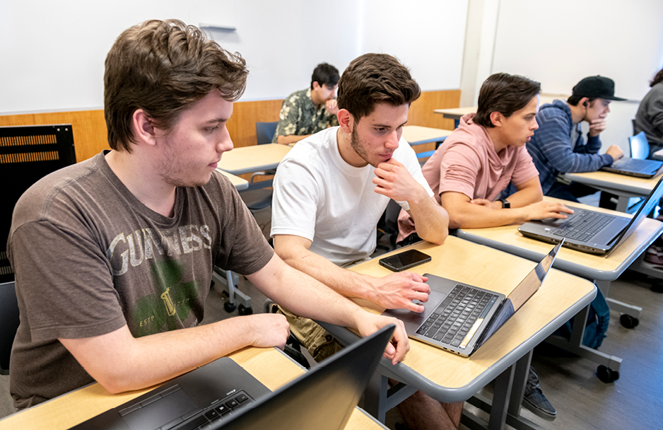 Two students working on a laptop together