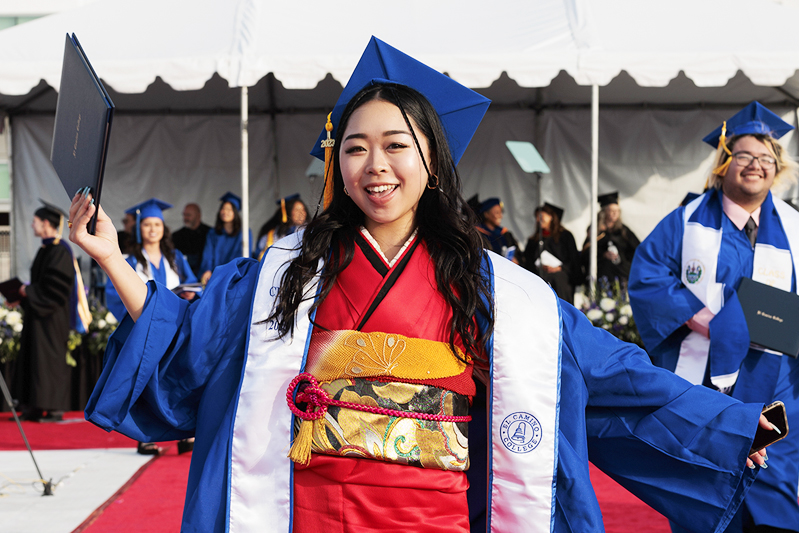 Smiling grad holding diploma.