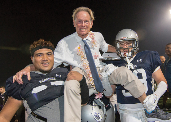 Football players holding Coach Featherstone on their shoulders in celebration.