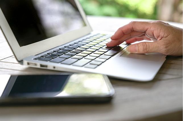 Hand typing on a laptop keyboard.