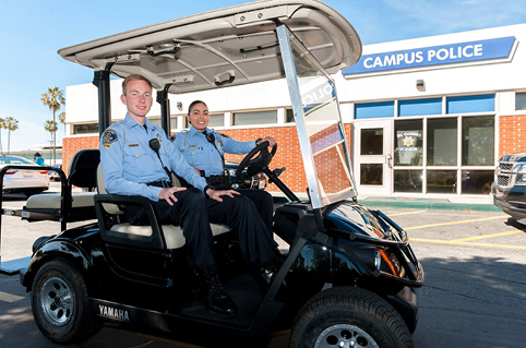 Cadets smiling inside the campus shuttle in front of the police station.