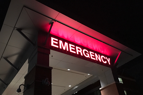 Red "emergency" sign at the front of a hospital at night