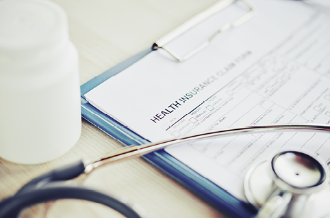 Stethoscope sits on top of clipboard with insurance papers on it 