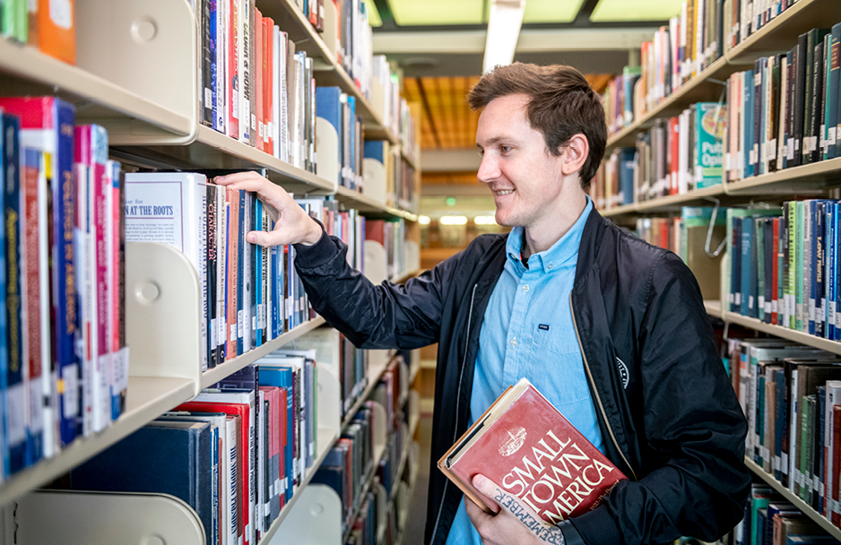 Student taking a book off the shelf in the library