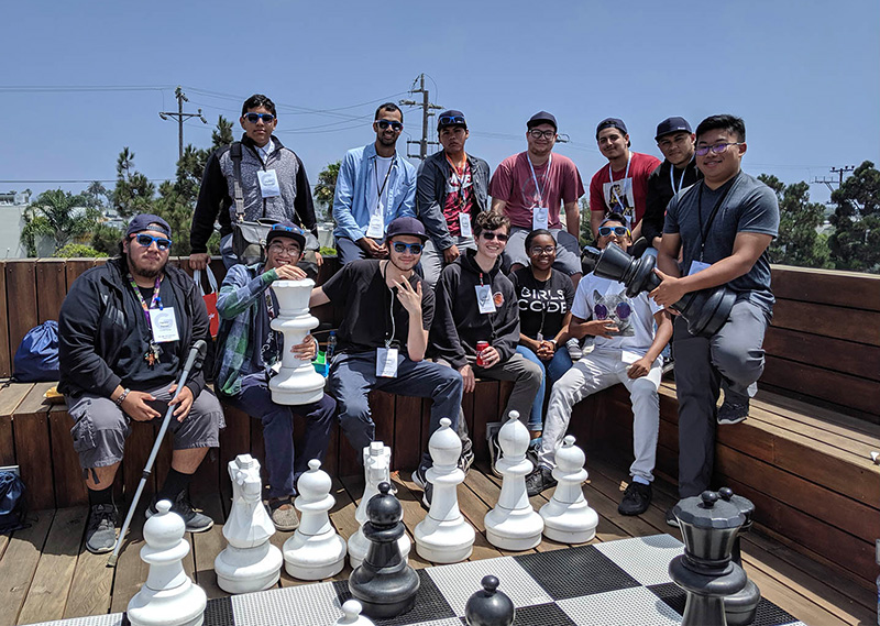 Students next to large-sized chess pieces